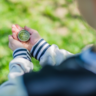 Ein Junge hält einen Kompass in der Hand zur Wegefindung