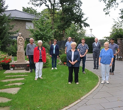 Die Caritas Mitarbeiter stehen auf einem Gruppenbild im Garten zusammen